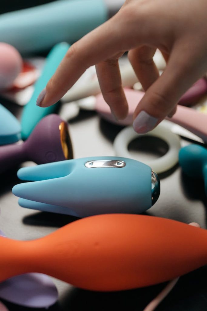 Close-up image of diverse vibrators with hand reaching out.